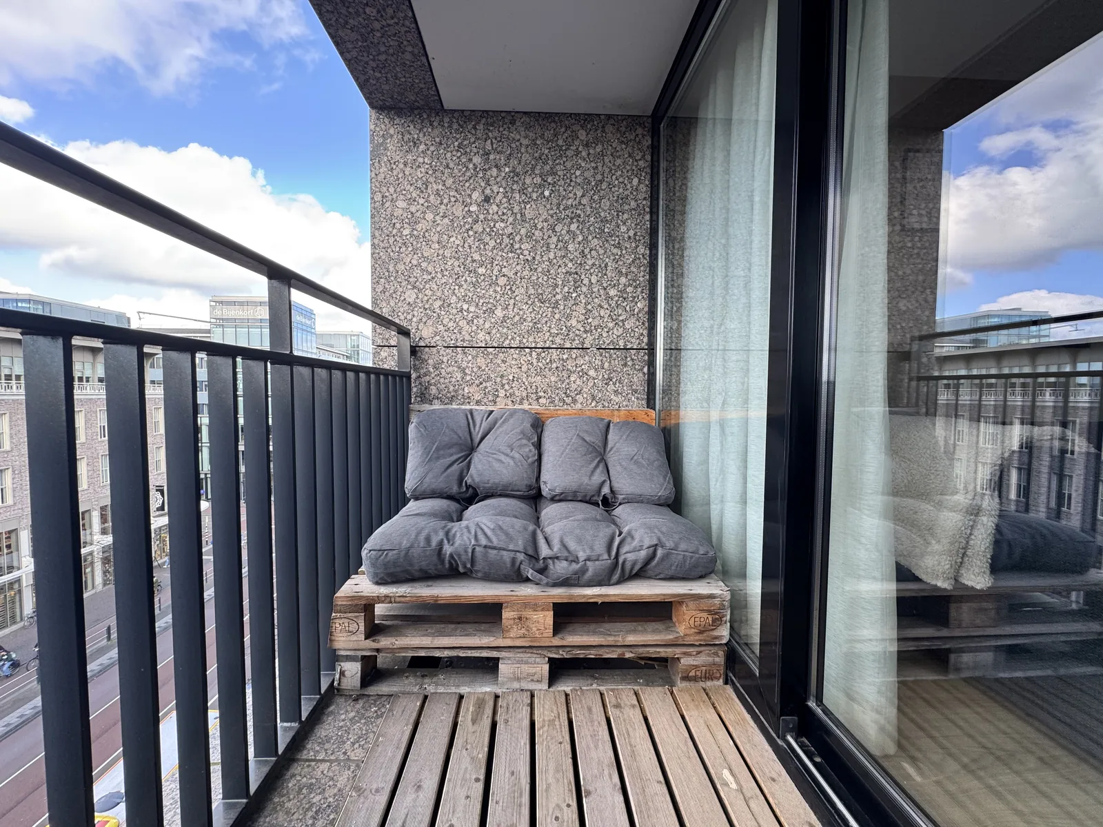 Close-up of pallet lounge sofa with cushions on apartment balcony overlooking Utrecht buildings
