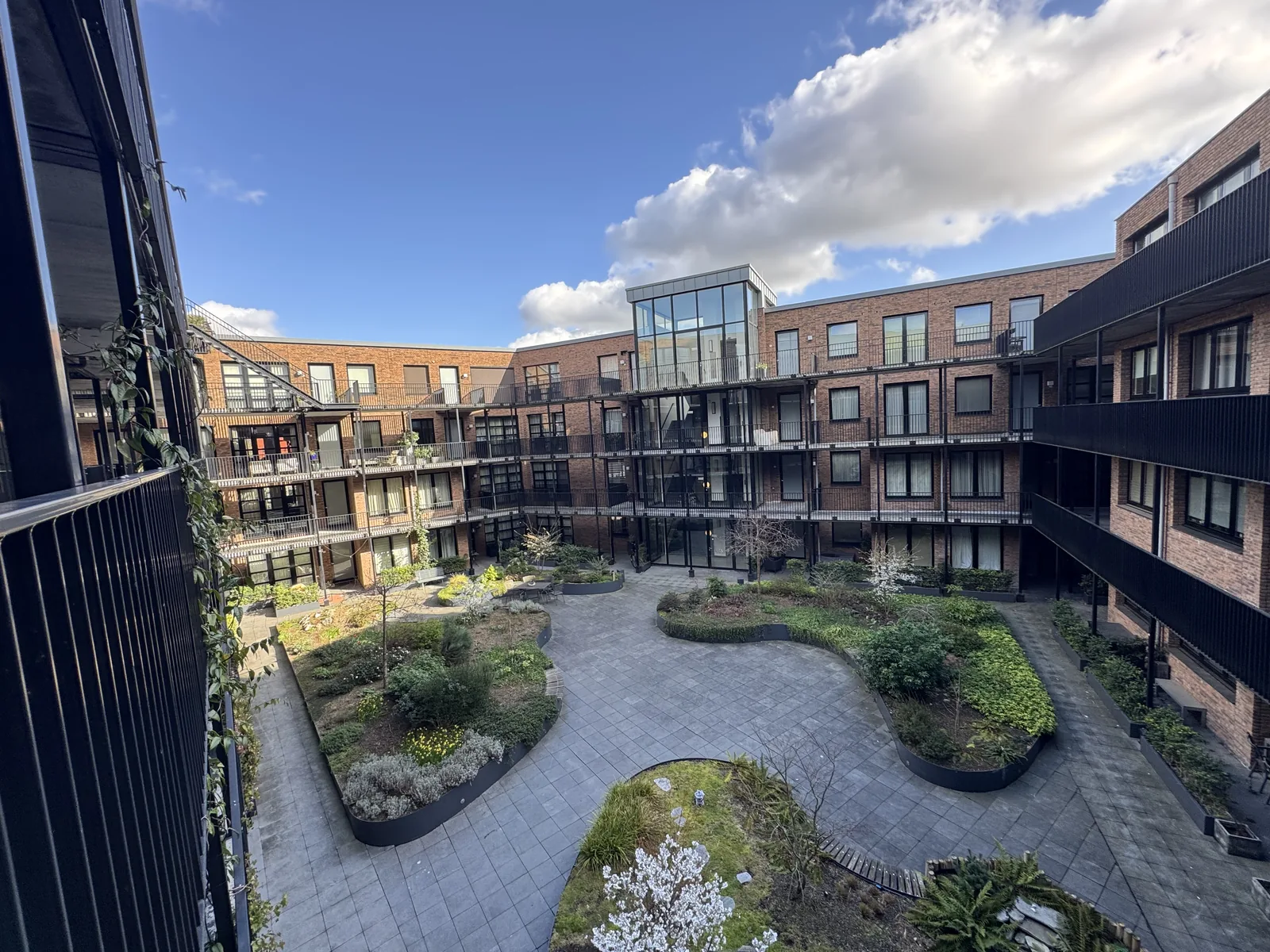 Landscaped inner courtyard garden with greenery, walking paths, and surrounding apartment building in Utrecht