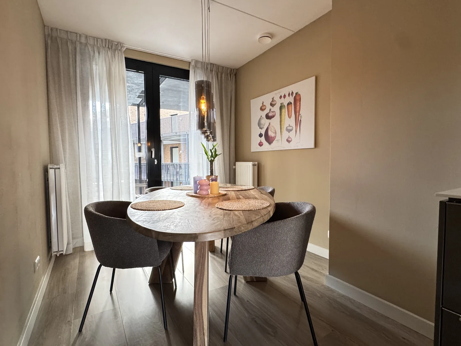 Cosy dining area with round solid wood table, upholstered chairs, and pendant lights in Utrecht Vredenburg apartment