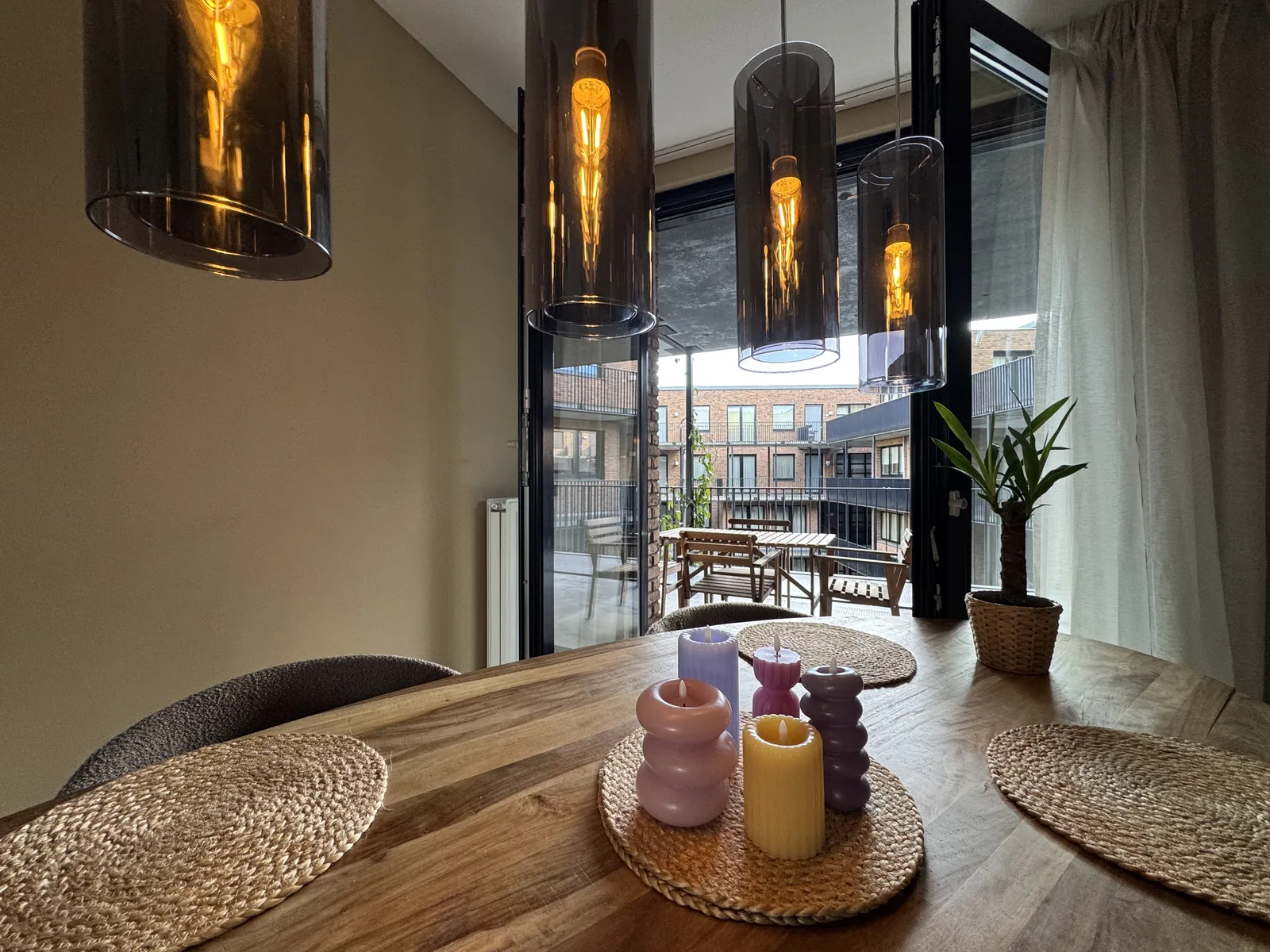 Evening atmosphere at dining table with warm pendant lighting, candles, and terrace view in Utrecht apartment