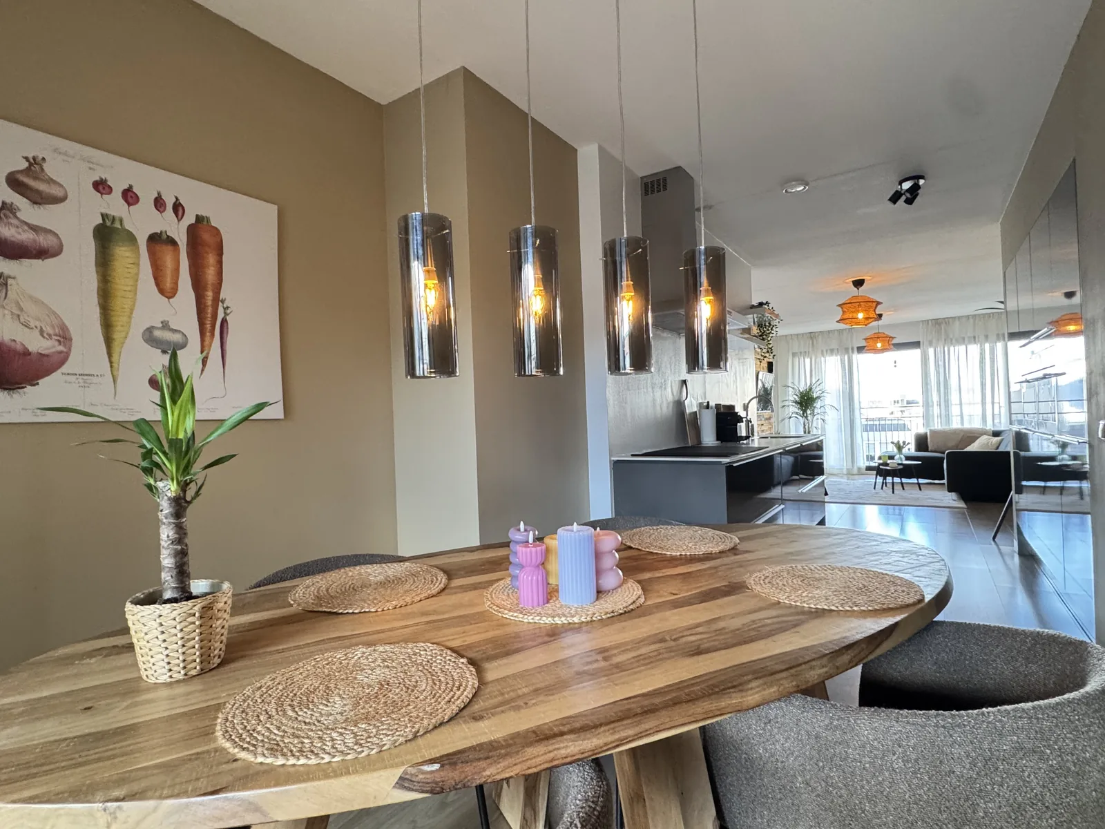 Dining table with smoked glass pendant lights, botanical artwork, and view through to kitchen and living room