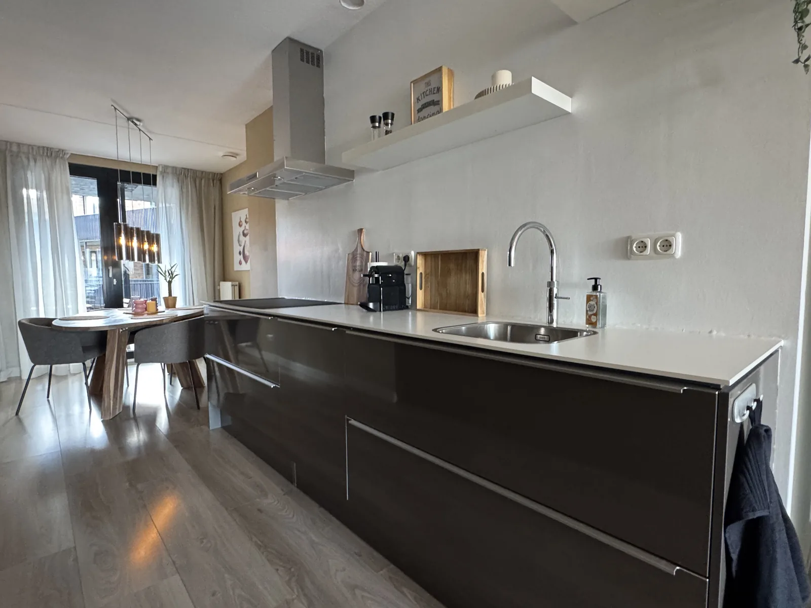 Kitchen island with stainless steel sink, range hood, and Nespresso machine in modern Utrecht city centre apartment