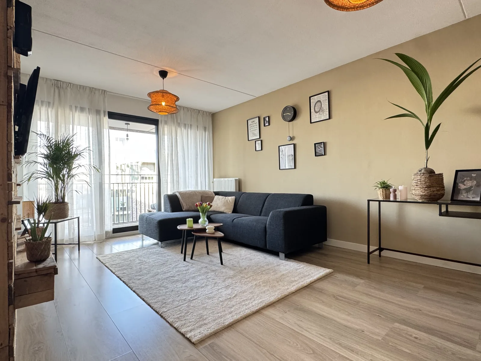 Modern living room with dark grey sectional sofa, designer pendant lamp, and city view balcony in Utrecht centre