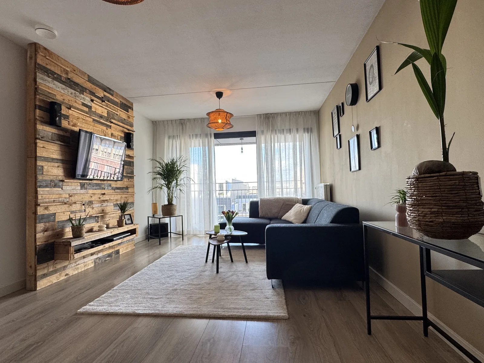Wide-angle view of furnished living room showing balcony doors, pendant lighting, and modern decor in Vredenburg apartment