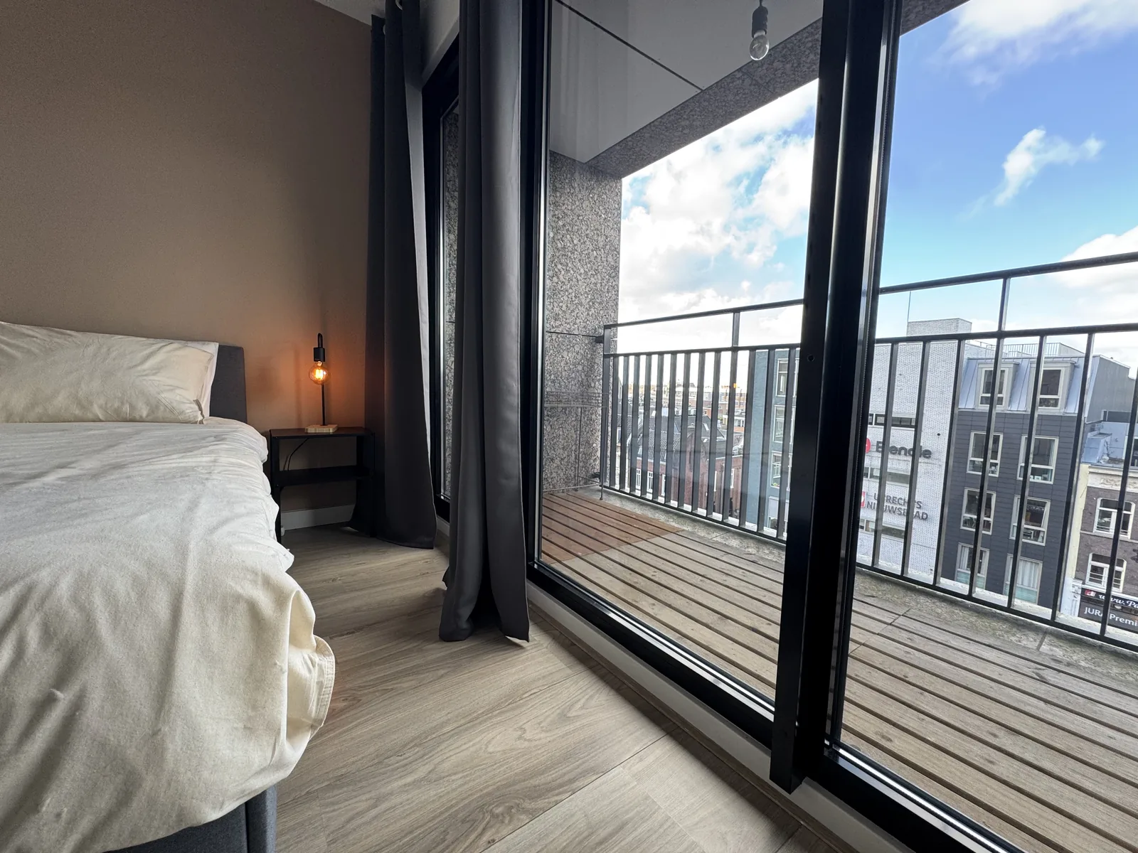 View from master bedroom through open balcony doors showing Utrecht skyline and Blendle headquarters