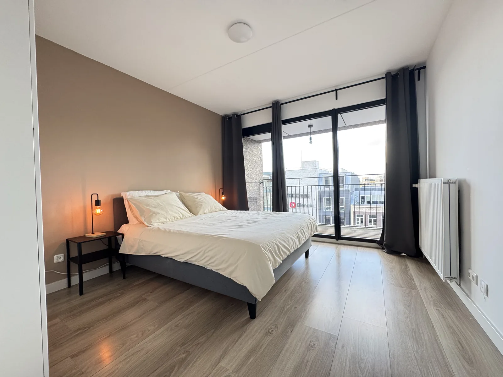 Master bedroom with double bed and floor-to-ceiling windows overlooking Utrecht