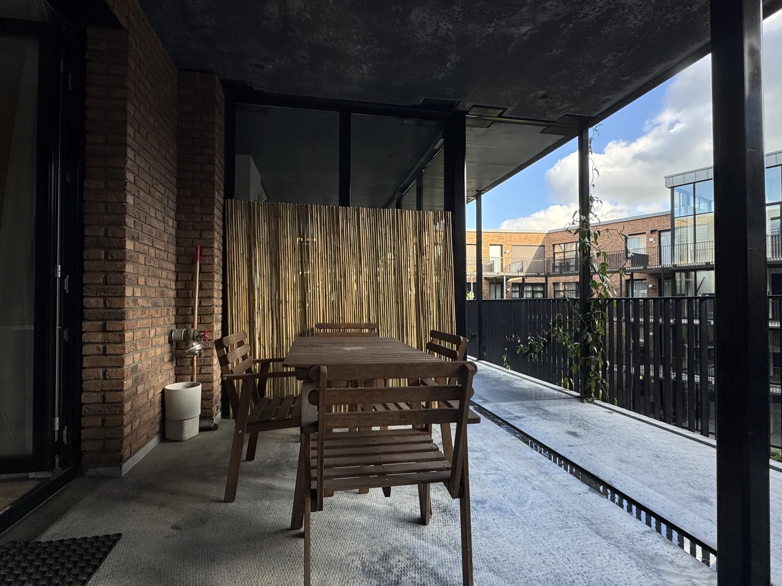 Private covered terrace with wooden dining table and chairs, bamboo screen, overlooking courtyard garden