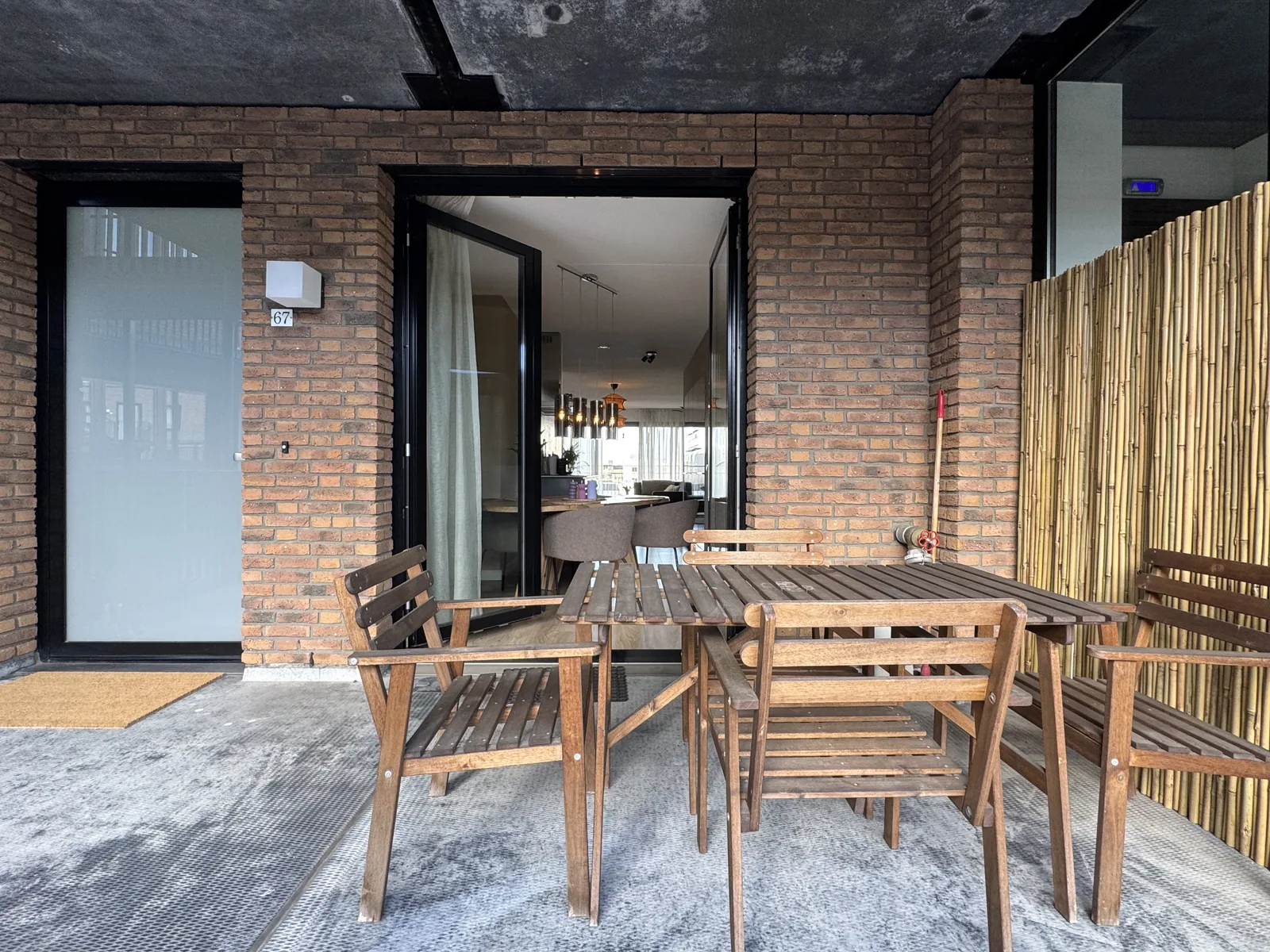 Terrace entrance with brick facade, wooden outdoor furniture, and apartment number visible at Utrecht complex