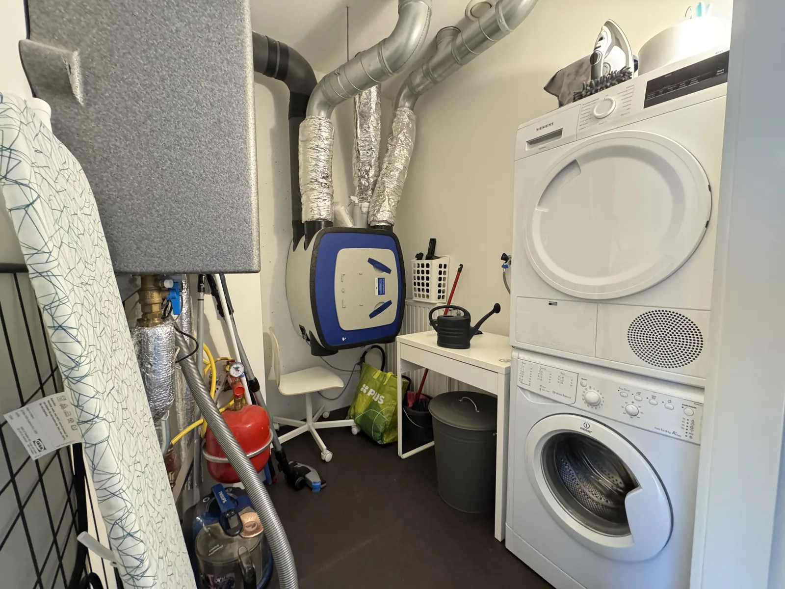 Utility room with stacked washing machine and dryer, ventilation system, and storage in Utrecht rental apartment